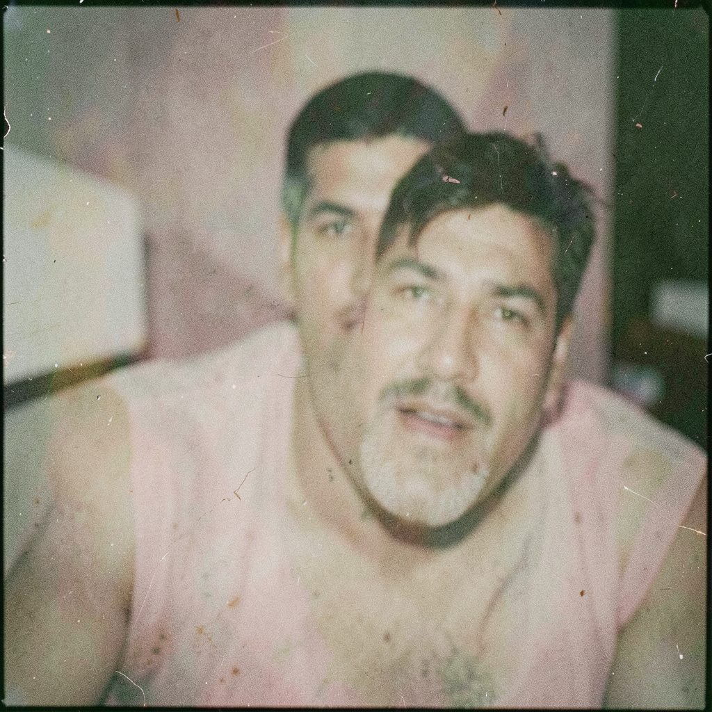 A grainy analog film photograph of a soft pinkish powder resting on a dark slate surface, muted rose and charcoal tones, dimly lit and atmospheric.