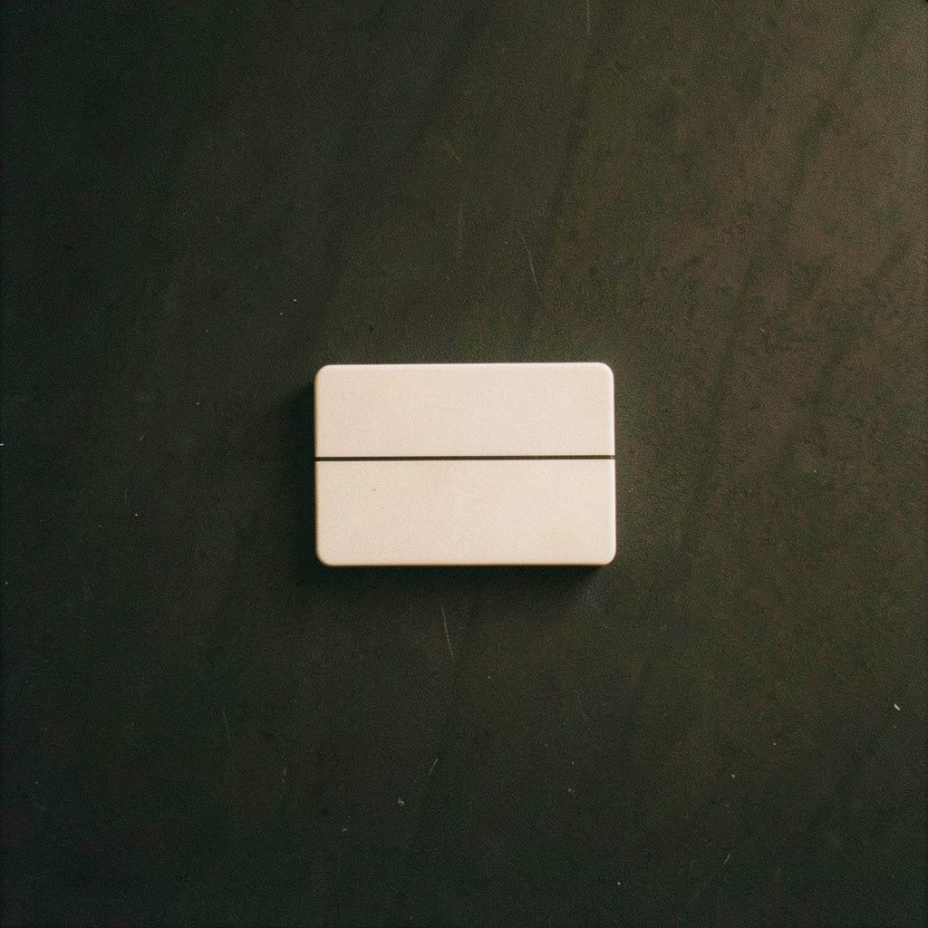 A grainy film photograph of a small white tablet with score line, placed on a dark matte surface under dim warm light.